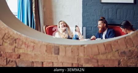 Freunde, lachende und Frau mit Telefon im Café, Bonding und Ansehen von Comedy-Show in der Social Media App. Coffee Shop, Gastfreundschaft und glückliche Menschen mit Stockfoto