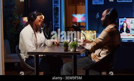 Frau hostet Podcasts mit professionellen Audiogeräten, um eine hohe Klangqualität bei Live-Gesprächen mit Gästen zu gewährleisten. Internet-Show Moderator spricht mit Mann, sendet aus dem Heimstudio Stockfoto
