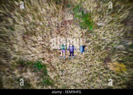 Luftaufnahme von oben auf dem Feld liegendes Paar, Bewegungsunschärfe Zoom-Effekt für dynamische Perspektive, Draufsicht auf Menschen in der Natur mit abstraktem radialem Bewegungsmuster Stockfoto