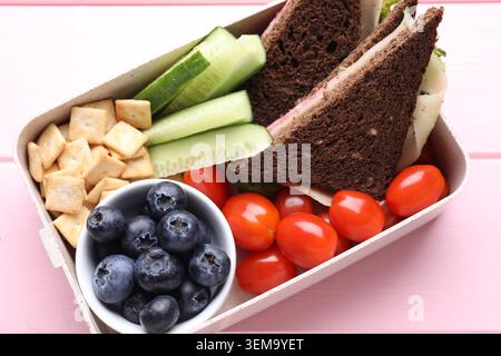 Lunchbox mit leckerem Essen auf rosa Holztisch, Blick von oben Stockfoto