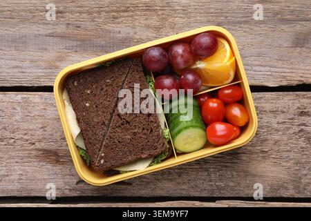Lunchbox mit leckeren Speisen auf Holztisch, Blick von oben Stockfoto
