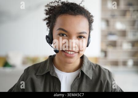 Lächelnde, freundliche Mischstudentin im Headset, Blick in die Kamera, Online-Lernen. Kopffoto-Porträt eines zweirassigen Teenager-Mädchens in Kopfhörern mit Mikrofon. Fernunterricht, elearning-Konzept. Stockfoto