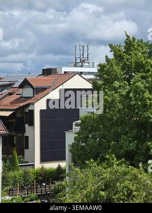 Solarpaneele auf Dach und Wand in Deutschland – moderne Photovoltaik-Solarpaneele, die sowohl auf Dächern als auch auf Gebäudefassaden installiert sind und die deutsche Kommunikation zeigen Stockfoto