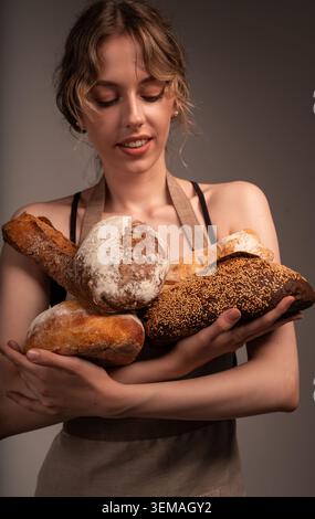 Junge Bäckerin mit frischen, handwerklichen Brotlaiben und Bio-Backwaren Stockfoto