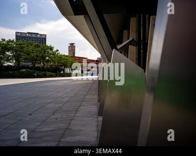 Flacher Blick auf die Außenansicht des modernen Gebäudes mit scharfen geometrischen Metallelementen und Betonplatz Stockfoto