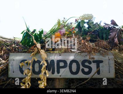 Rustikaler Holzkompost Schild auf Einem Haufen von Gartenabfällen und toten Blumen Stockfoto