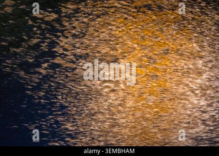 Abstrakte ICM-Aufnahme (Intent Camera Movement) mit goldenem Licht auf einer dunkelblauen Oberfläche, die eine fließende, energetische Textur mit Bewegungsunschärfe A erzeugt Stockfoto