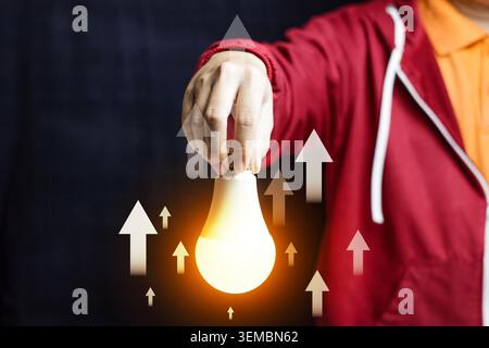 Konzept für steigende Energiekosten mit handgehaltener Glühbirne und Aufwärtspfeilen. Wachstum. Innovation, Strategie und Lösungskonzept. Hochwertige Fotos Stockfoto