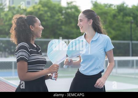 Weibliche Pickleball-Spieler lachen mit Paddeln auf dem Platz Stockfoto