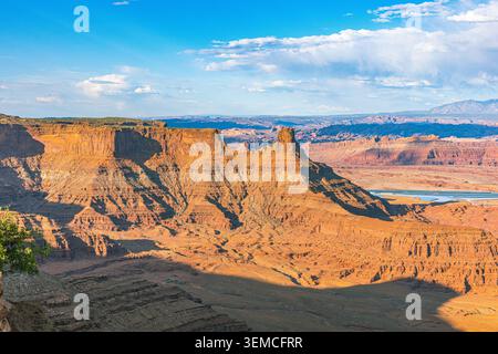 Sonnenbeschienene rote Felsmesas und tiefe Canyons erstrecken sich unter blauem Himmel in Richtung des Colorado River im Dead Horse Point State Park, Utah. Stockfoto