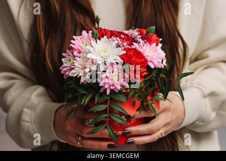 Frau mit bunten Blumenstraußen aus der Nähe. Frisches Blumengeschenk für Feiern, romantische Anlässe, Hochzeiten und besondere Anlässe. Stockfoto