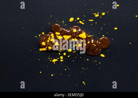 Tropfen acrylbraune und gelbe Farbe auf schwarzem Papier als Hintergrund Stockfoto