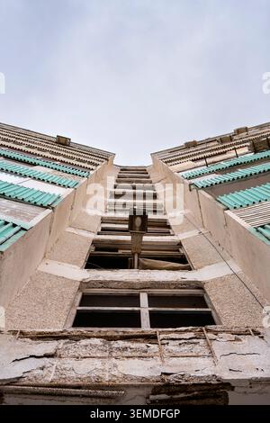 Flacher Blick auf eine verwitterte Fassade eines Wohngebäudes aus der Sowjetzeit in Usbekistan, Zentralasien, mit sich wiederholenden Balkonen, abgenutztem Beton und blassem Stockfoto