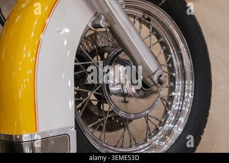 Nahaufnahme erfasst Vorderrad und Kotflügel des Motorrads. Der zweifarbige Kotflügel ist in glänzendem weiß und leuchtendem Gelb mit orangefarbenem Nadelstreifen und chr-Schriftzug gehalten Stockfoto