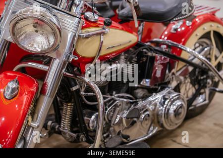 Die Nahaufnahme zeigt ein Motorrad in Vintage-Rot und Creme mit glänzendem Chrom-Lenker, Scheinwerfer und Motor. Komplizierte Details heben den hervor Stockfoto