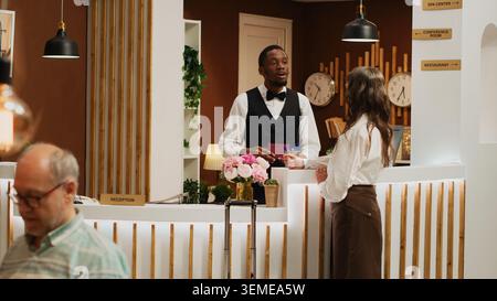 Der Hotelkoncierge überprüft den Reisepass für die Zimmerreservierung im 5-Sterne-Resort und hilft Seniorinnen beim Check-in. Das Personal an der afroamerikanischen Rezeption überprüft die persönliche ID des Gastes. Stockfoto