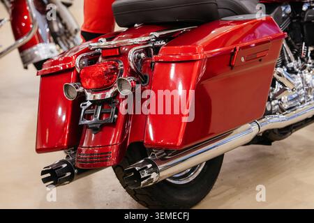 Detaillierte Nahaufnahme erfasst den hinteren Teil eines rot leuchtenden Motorrads. Zu den Merkmalen gehören geräumige Satteltaschen und ein integriertes Rücklicht mit orangefarbener Blinkleuchte Stockfoto