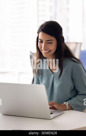 Lächelnde Geschäftsfrau, die am Arbeitsplatz am Laptop arbeitet Stockfoto