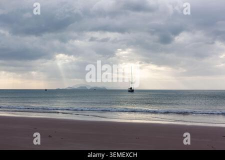 Segelboot vor Anker in der Nähe von Ao Son Beach. Blick auf die Inseln Lipe und Adang in der Ferne. Koh Tarutao Nationalpark mit bewölktem Himmel und ruhigem Meer. Stockfoto