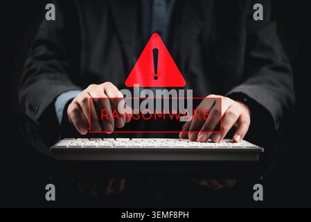 Geschäftsmann tippt auf der Tastatur mit rotem Ransomware-Warnhologramm. Cybersicherheitskonzept mit Malware-Angriffen, Datenmissbrauch und Systemverschlüsselung W Stockfoto