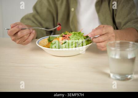 Nahaufnahme einer älteren Frau, die eine Gabel hält und zu Hause einen frischen Salatschüssel isst. Ältere Menschen gesunder Lebensstil, organische Ernährung, Gewichtsverlust, und ve Stockfoto