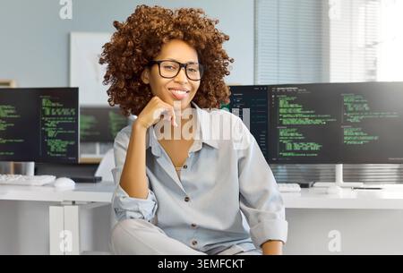 Selbstbewusste Programmiererin am Computer in modernen Büros, codiert auf zwei Bildschirmen Stockfoto