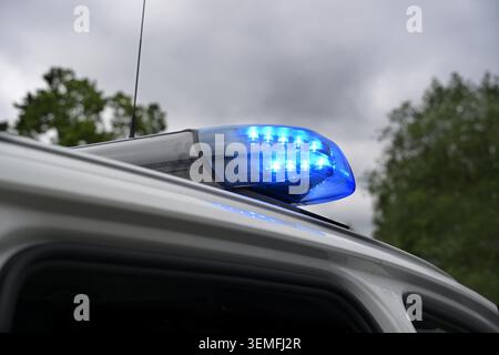 Blinkender blauer Lichtbalken an einem deutschen Polizeiauto vor dunklem bewölktem Himmel, Warnsignal während einer Operation zum Schutz der Öffentlichkeit, Kopierraum, ausgewählter Fokus Stockfoto