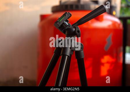 Nahaufnahme eines schwarzen Kamerastativs, das drinnen steht, mit verschwommenem Hintergrund und geringer Schärfentiefe. Stockfoto