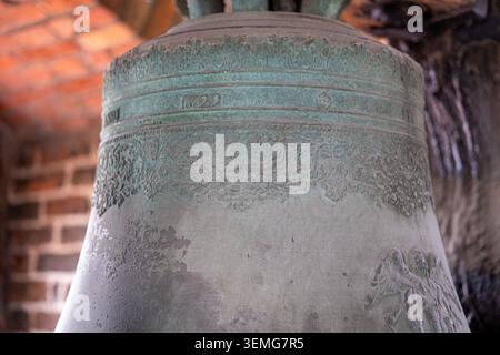 : Nahaufnahme einer antiken Bronzeglocke zeigt das Gussjahr 1729 und verzierte Blumenmuster. Stockfoto