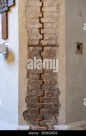 Freiliegender vertikaler Mauerwerk-Abschnitt befindet sich neben weißen verputzten Säulen in einem historischen Kircheninnenraum. Stockfoto
