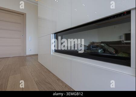 Moderne Einrichtung mit elegantem, eingebautem Kamin. Heller Holzfußboden und eine bündige Tür unterstreichen die klaren Linien des Raumes Stockfoto