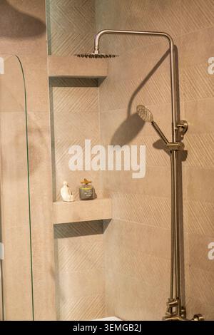 Zeitgenössisches Bad-Design mit goldfarbener Regendusche und Chevron-Wand Stockfoto