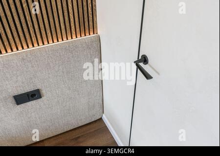 Nahaufnahme eines modernen Innenraums mit Tür, Wandpaneel, Holzlatten und Steckdose Stockfoto