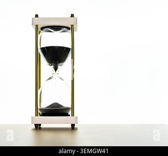Sanduhr aus schwarzem Sand auf weißem Hintergrund, Zeitvertreib und Countdown-Konzept für Business, Deadline, Geduld, Fokus und minimalistische Dekorationsbilder heute Stockfoto