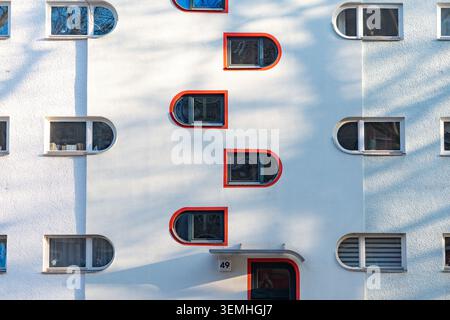 Abgerundete rot gerahmte Fenster an weißer Fassade, Scharoun-beeinflusstes Gebäude der 1960er Jahre, Motzstraße, Berlin Stockfoto