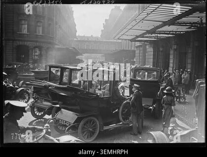 Agence Rol registriert Taxis, die am 13. August 1922 vor dem Gare Saint-Lazare in Paris anstehen, als sich Reisende zu Abfahrten versammeln, wobei Fahrzeuge und Passagiere in der Zwischenkriegszeit am Eingang des Bahnhofs einen stark frequentierten Verkehrsknotenpunkt bilden. Stockfoto