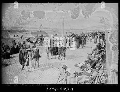 Am 17. April 1927 spazieren die Menschen entlang des Piers in Deauville, während sie die Küste des Kanals und die Küstenstrukturen bei ruhigen Frühlingsbedingungen beobachten. Stockfoto
