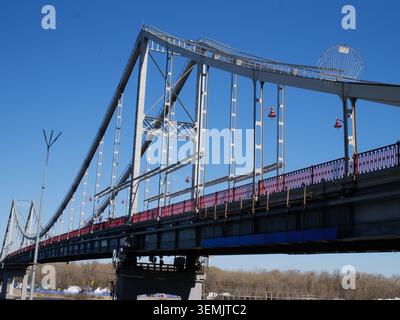 Malerische Landschaft einer Fußgängerbrücke mit Stahlbogen über den Fluss. Urbane Landschaft, Reiseziel und Outdoor-Freizeitkonzept in der Stadt Stockfoto