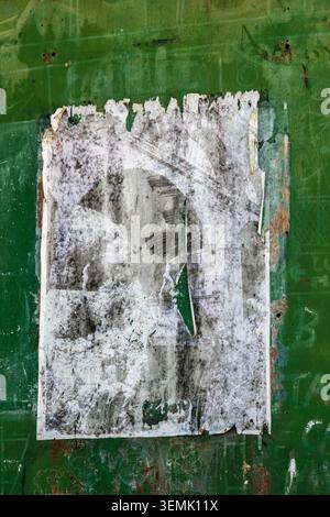Ein zerrissenes und verwittertes abblätterndes Poster auf einer lebendig grün bemalten Wand, die eine abstrakte, strukturierte urbane Kunstkomposition erschafft, La Grange Cafe, Frankreich Stockfoto
