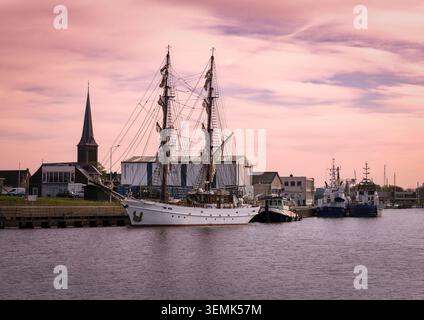 Traditionelle Segelboote liegen im Hafen von Lemmer, Niederlande, mit einem Teil der historischen Stadt im Hintergrund. Ein friedliches maritimes s Stockfoto
