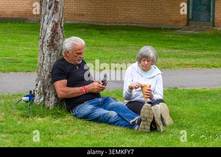 Ein Seniorenehepaar entspannt sich auf der Wiese beim Southport Food and Drink Festival in Southport, UK. Stockfoto