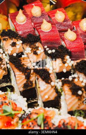Verschiedene Arten von Sushi werden auf einer Platte in einem Restaurant serviert. Das Sushi umfasst Lachs, Thunfisch und einzigartige Toppings. Diese Szene findet während statt Stockfoto