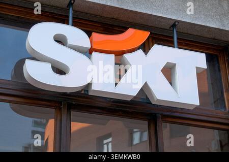 Lugano, Tessin, Schweiz - 24. Mai 2026: Nahaufnahme des leuchtend orangefarbenen Sixt Autovermietungsschildes an einer historischen Steinfassade. Trans Stockfoto