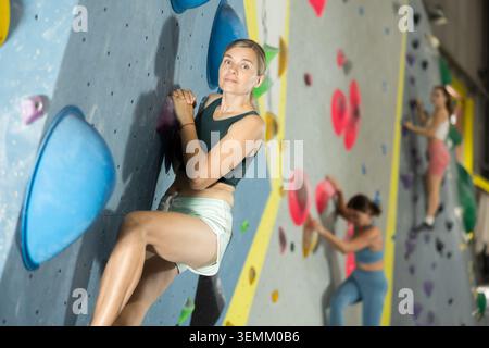 Frau, die schwieriges Klettern in der Kletterhalle macht Stockfoto