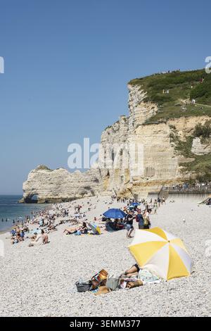 Zahlreiche Strandtouristen am Kiesstrand von Etretat mit den steilen Klippen der Falaise d'Amont an einem ungewöhnlich heißen Pfingstwochenende im Jahr 2026, E Stockfoto