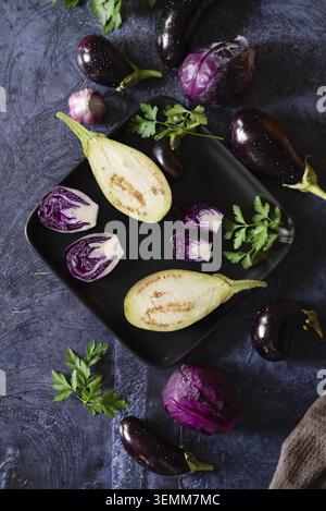 Auswahl an rohem Bio-Gemüse aus violettem Gemüse, Mini-Auberginen, Frühlingszwiebeln, Rote Bete, Radicchio-Salat, Pflaumen, Kohlrabi, Blütensalz auf Stockfoto