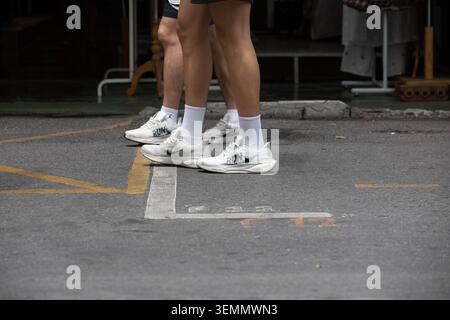 BANGKOK, THAILAND - 17. MAI 2026: Männliche Touristen in weißen Turnschuhen gehen, Nike Sneakers, ungeschützte Bewegung, natürliche offene Bewegung, Hochwinkelansicht Stockfoto