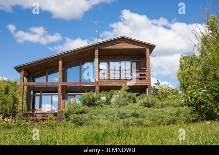 Modernes Holzhaus Mit Großen Panoramafenstern Und Angelegtem Garten In Abendsonne Stockfoto