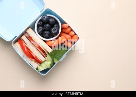 Lunchbox mit leckeren Speisen auf beigefarbenem Hintergrund, Blick von oben. Leerzeichen für Text Stockfoto