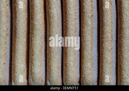 Ladyfinger Biscuits Reihe Makrostruktur Ladyfingers Hintergrund. Nahaufnahme von süßen, schwammigen Marienfinger-Keksen, bedeckt mit Zuckerkristall Stockfoto